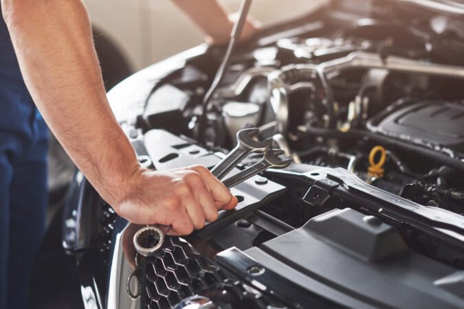 Picture showing muscular car service worker repairing vehicle.